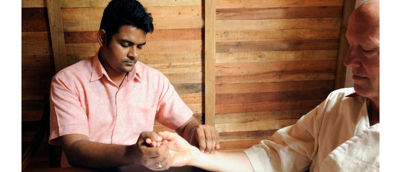 Therapist touches a man's arm with his eyes closed in a wood-panelled room