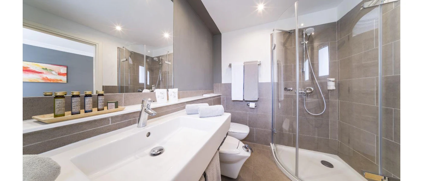 Stylish bathroom white white and glass furnishings, white towels and a large mirror