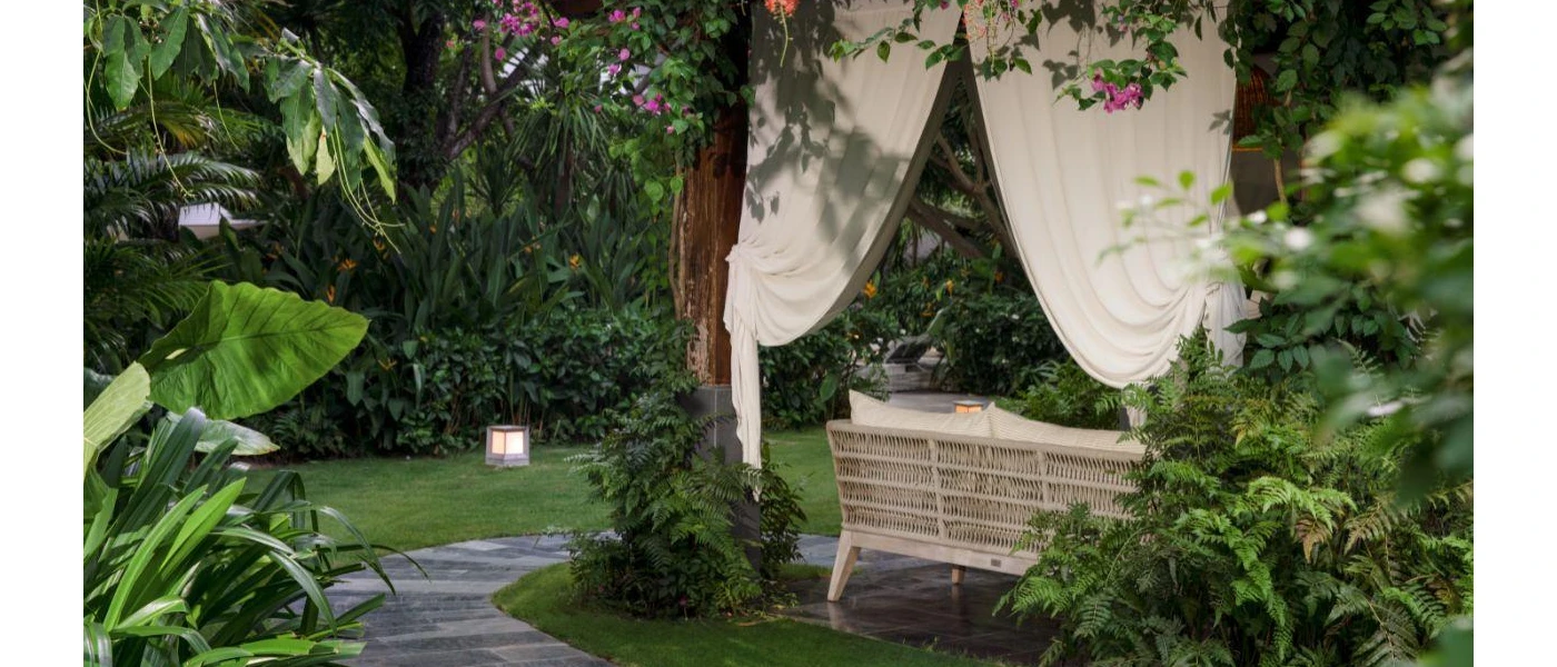 Garden courtyard with a seating area draped in white fabric and with a rattan sofa