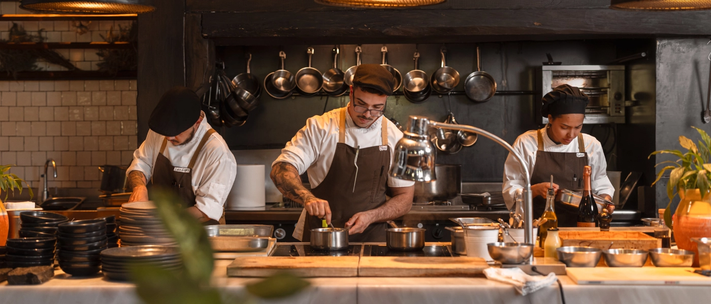 Staff members in an aprons works behind a counter in a room filled with produce