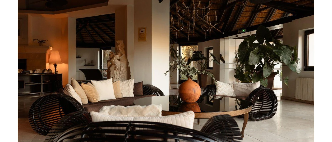 Airy lobby with marble floors, glossy plants, Hindu statues and dark-wood rattan furniture with white cushions