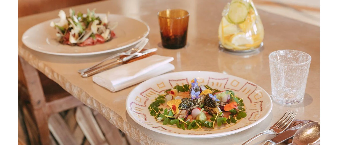 Intricately presented salads on white plates, with edible flowers and caviar garnishes