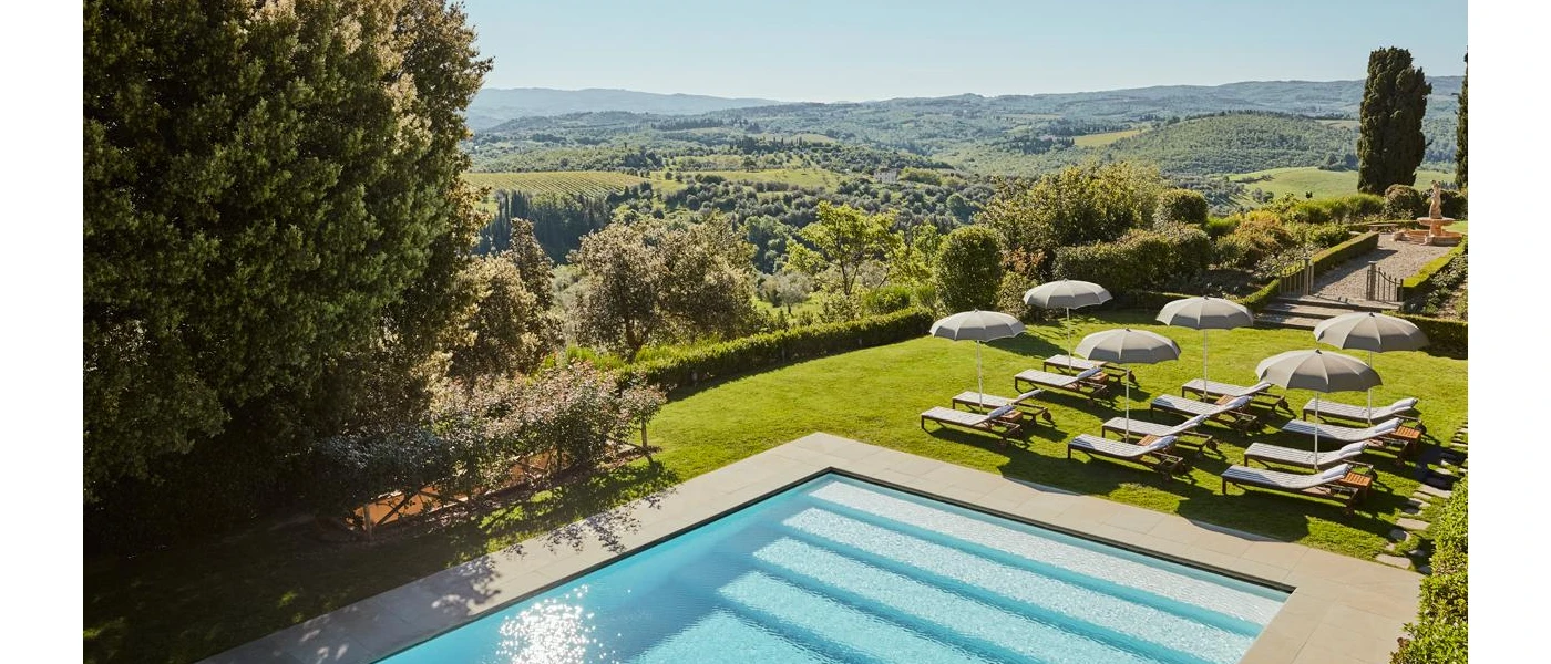 Steps into a swimming pool in a lawned terrace overlooking the countryside, complete with white loungers and parasols