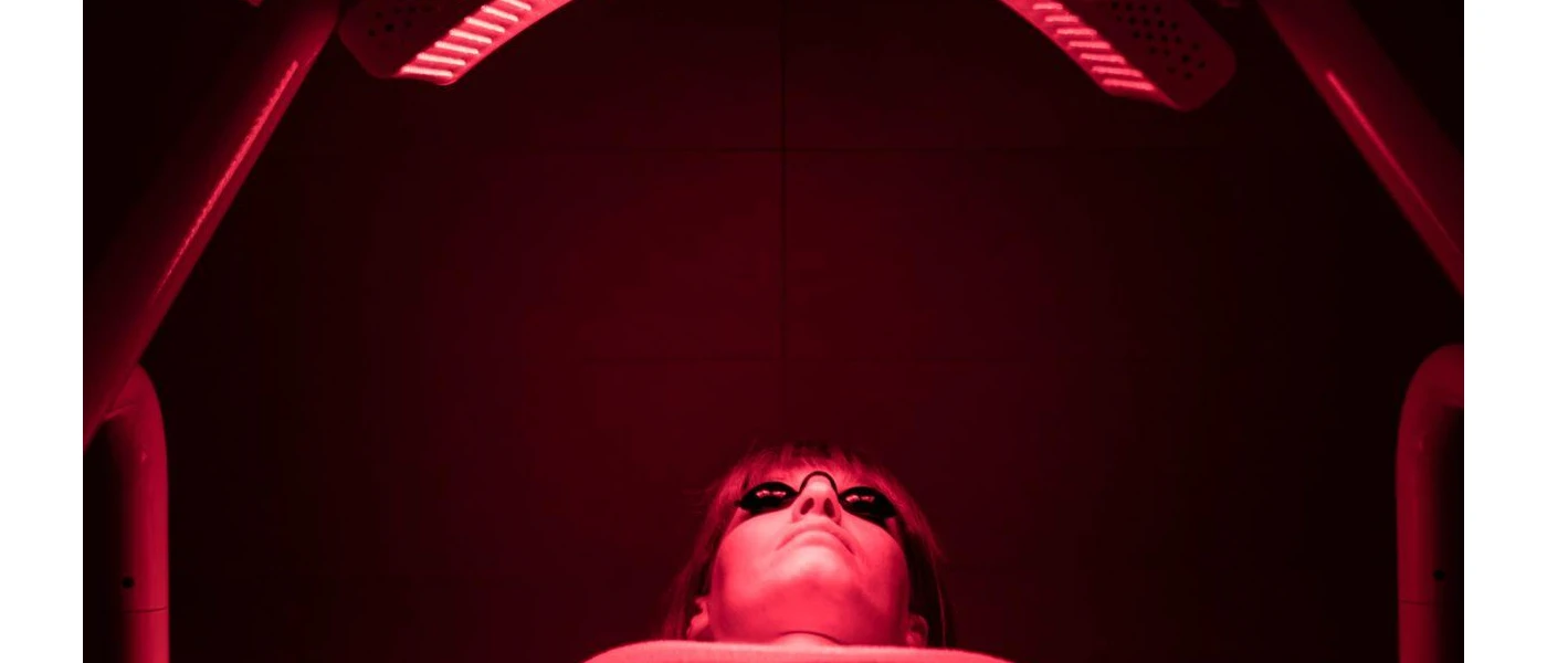 Woman lies under red infrared light with protective glasses on  