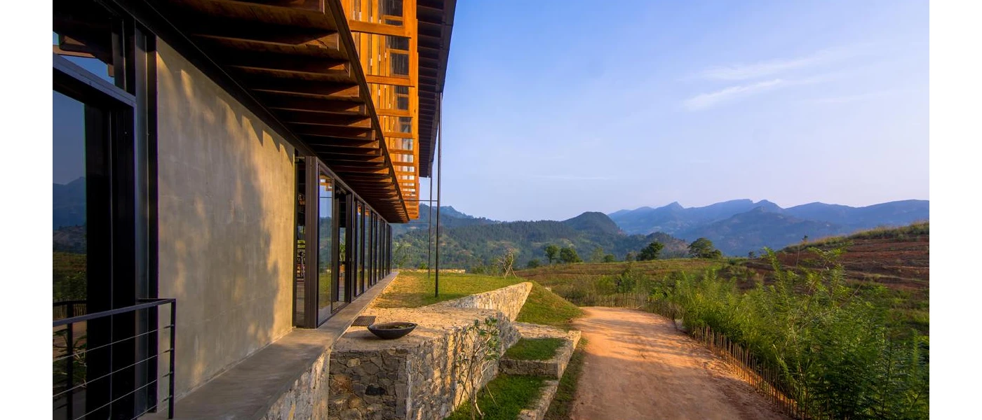 Wooden and stone building overlooking mountains and tropical greenery under a blue sky