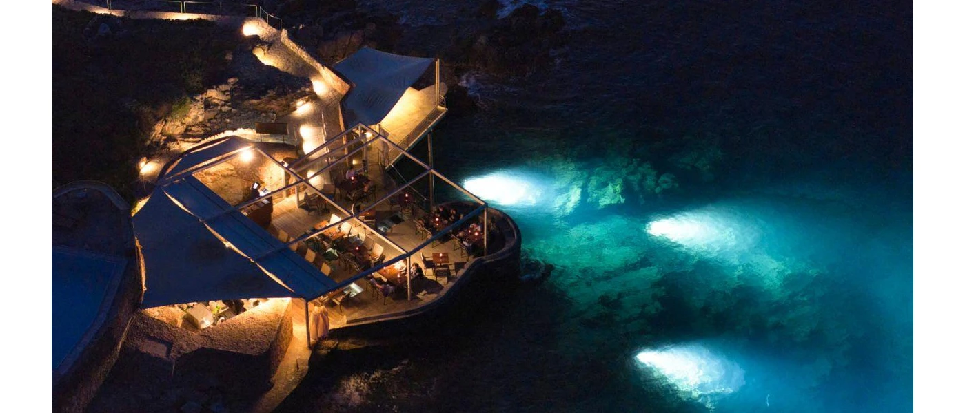 Cliffside restaurant with an al fresco dining terrace and in-water lights showcasing the rocks in the sea below