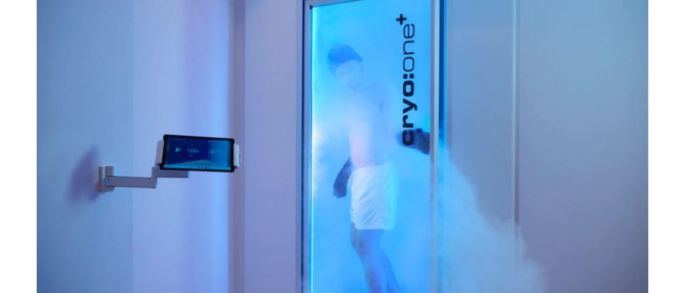 Man in white shorts in a blue-lit cryotherapy chamber 