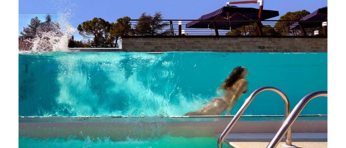 Woman swimming underwater, seen from a glass window from a pool a level down