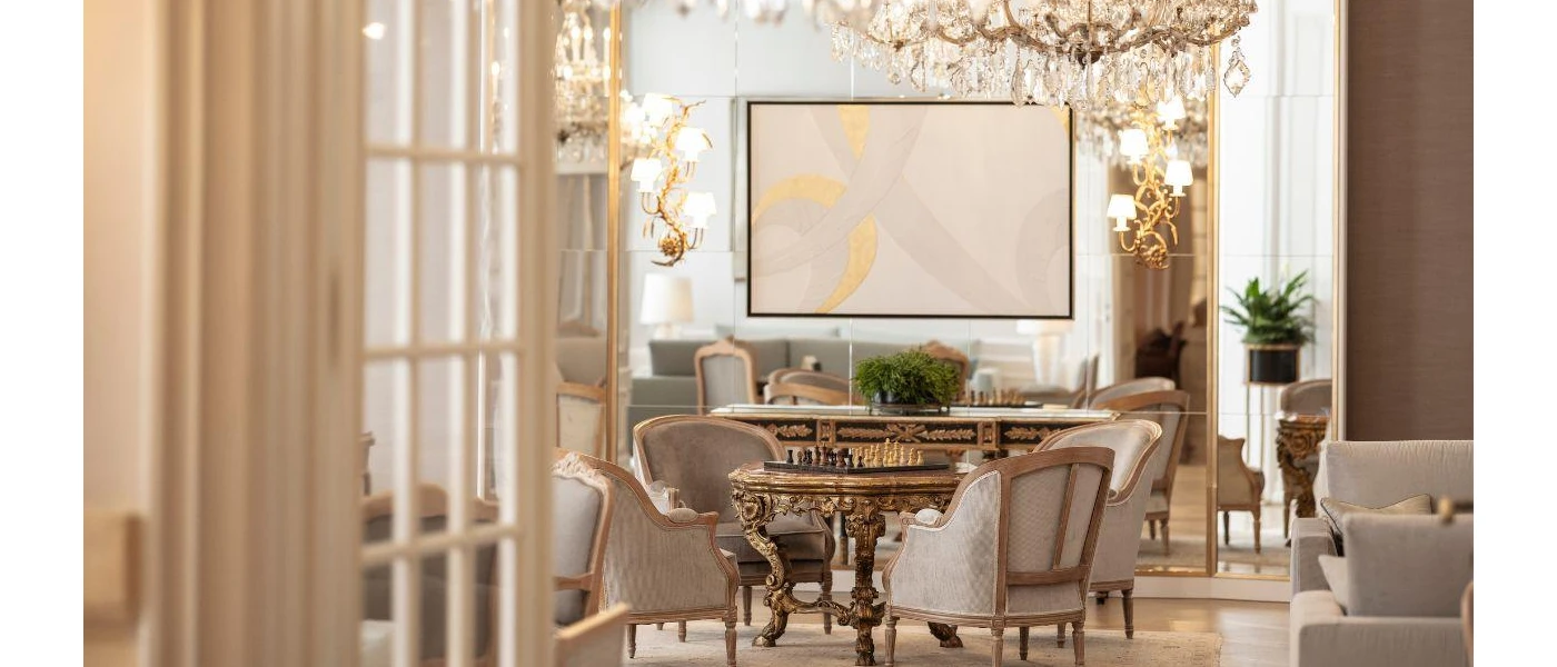 Elegant lounge area with wooden floors, chandeliers, gilded mirrors, patterned rugs and grand armchairs