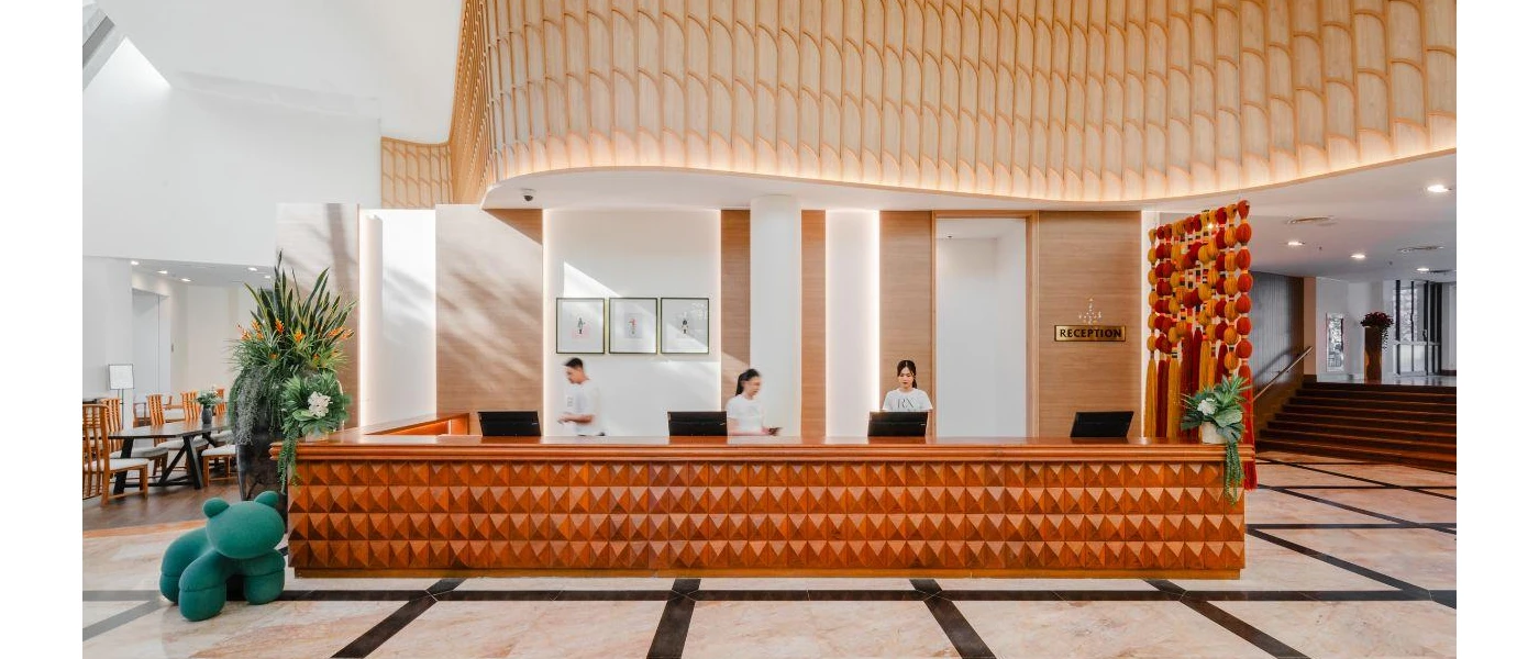 Airy reception with a wooden desk, white walls and ceilings and staff members in white uniforms