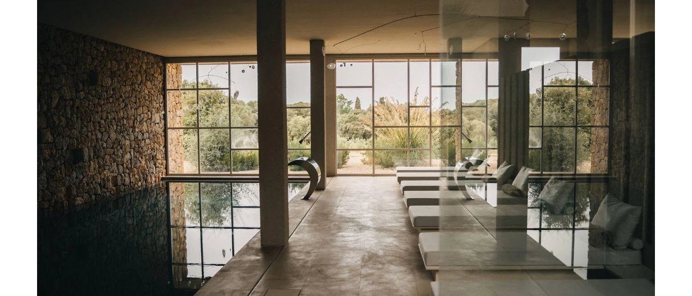 Indoor swimming pool and loungers with floor-to-ceiling windows overlooking the countryside