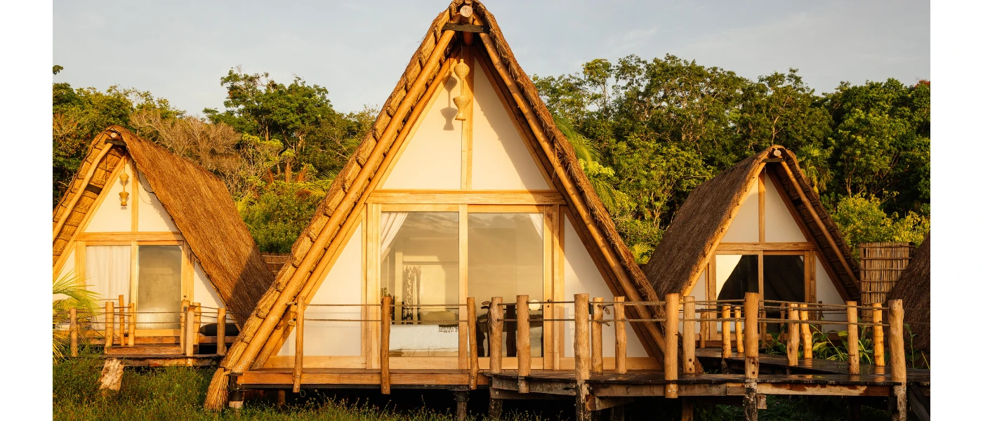 Thatched-roof A-frame villas with wooden terraces backed by jungle