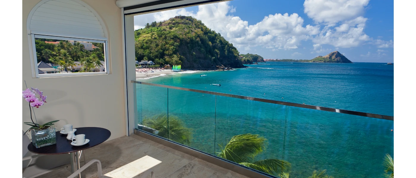 Ocean view room with a large window overlooking the sea and a seating area 