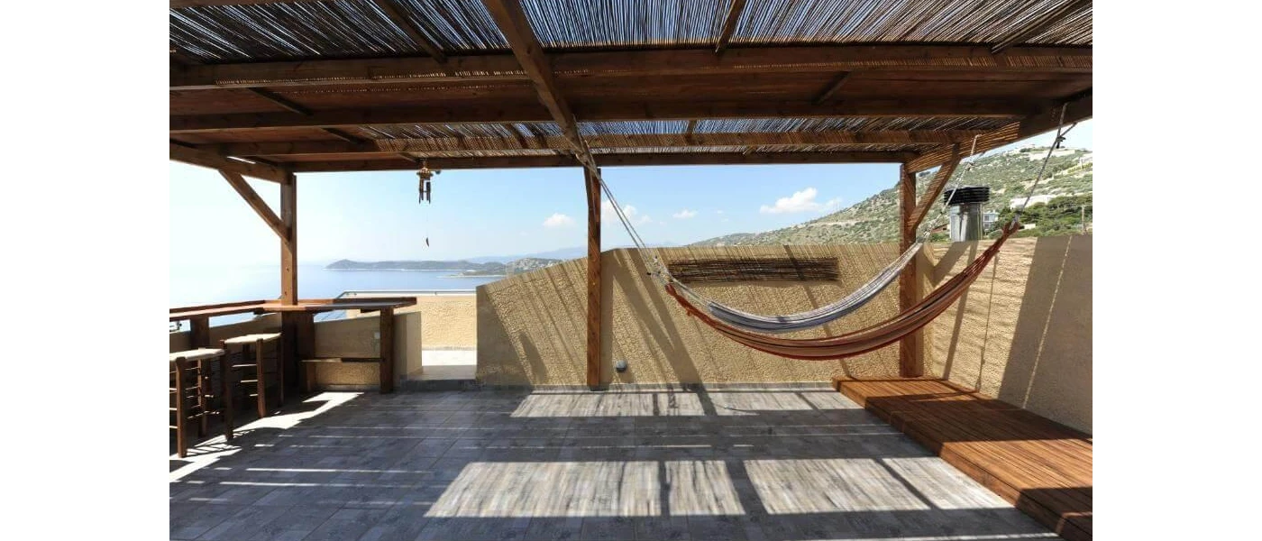 Thatched-roof wooden terrace with two hammocks, open sides and a sea view