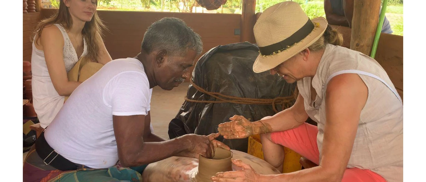 Woman in a straw hat tries pottery with a local instructor, as another woman watches on