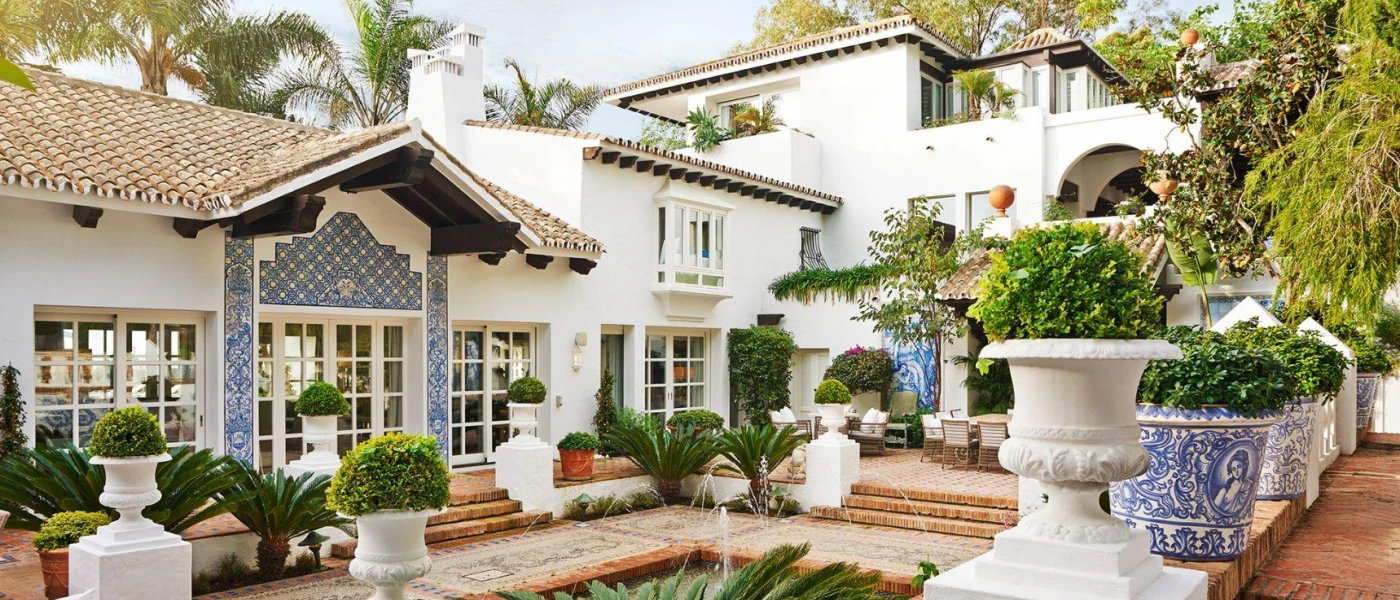 Andalusian-style courtyard with a blue-tiled facade and plant pots, white buildings, terracotta rooftops and potted green plants