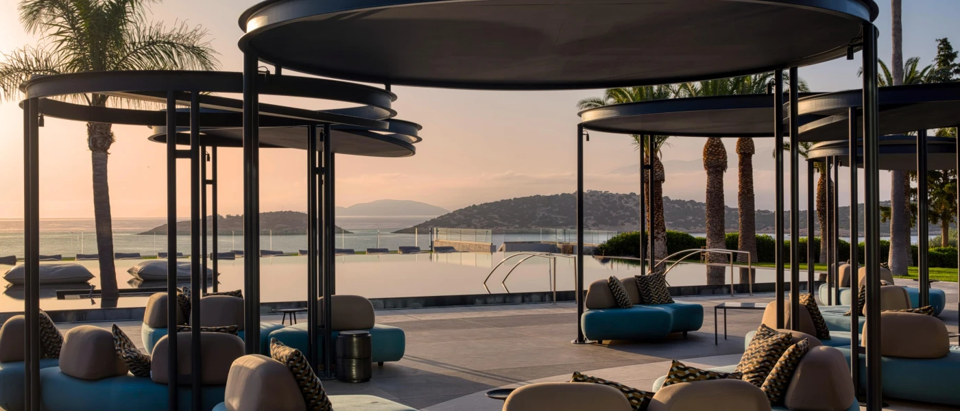 Blue and cream squishy armchair-style seating with rounded black pergolas on an ocean-facing poolside terrace  