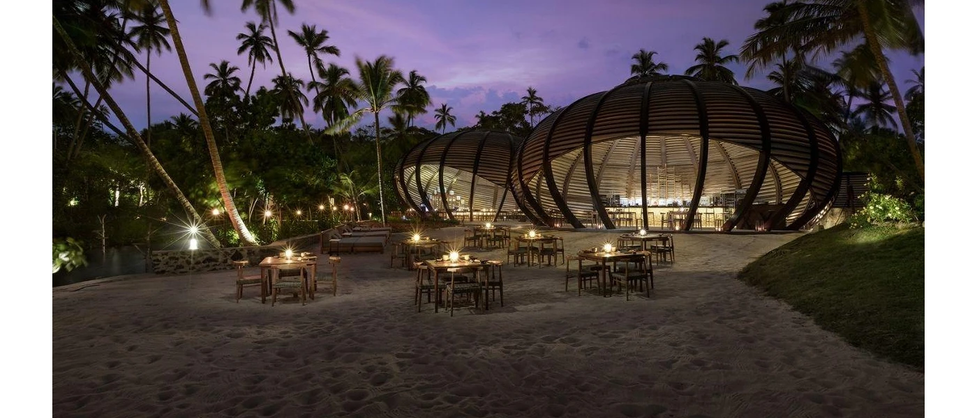 Bar with giant domed structure, overlooking the sand and tables and chairs lit by candlelight