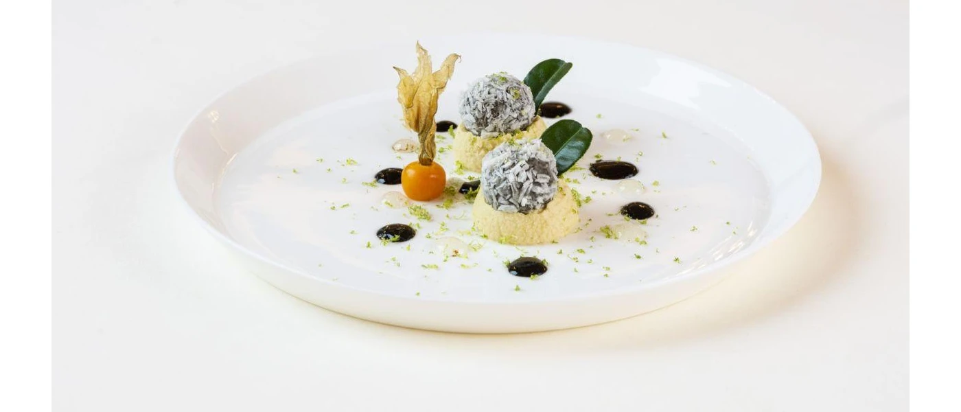 Inventive small bites of gourmet cuisine, including two balls sitting on potato mounds and an organic tomato