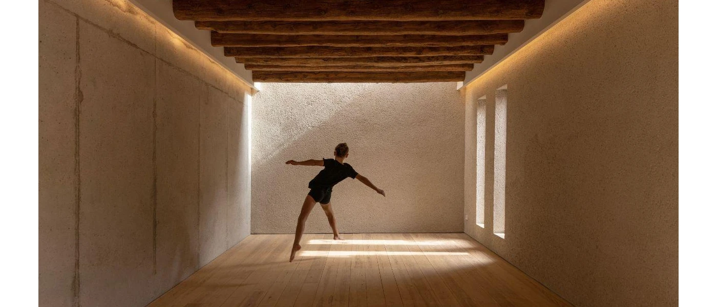 Person with arms outstretched in a neutral, softly lit room