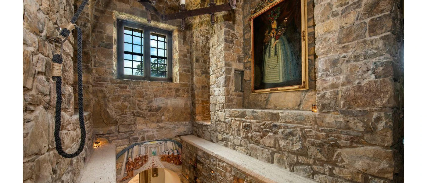 Stone corridor leading downstairs with an oil painting of an aristocratic woman hanging on the wall