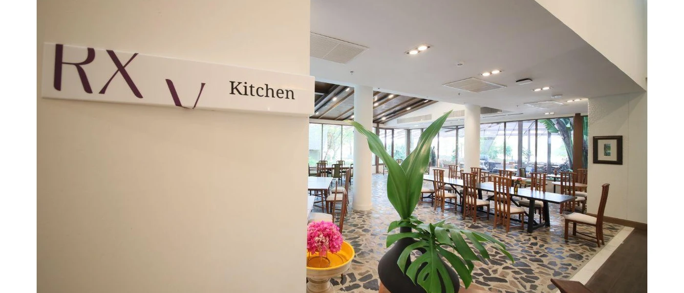 Spacious restaurant with wooden tables and chairs, a stone design floor and a sign reading RXV Kitchen