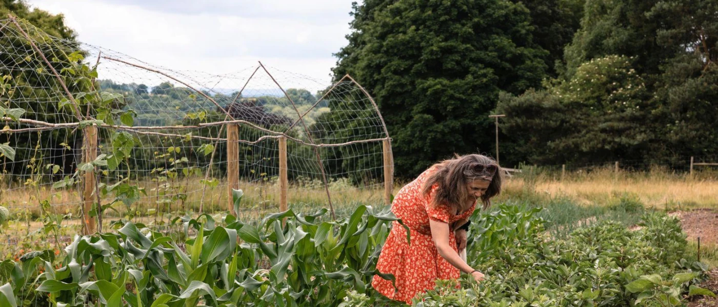 Lady in a red dress picking ingredients in a garden