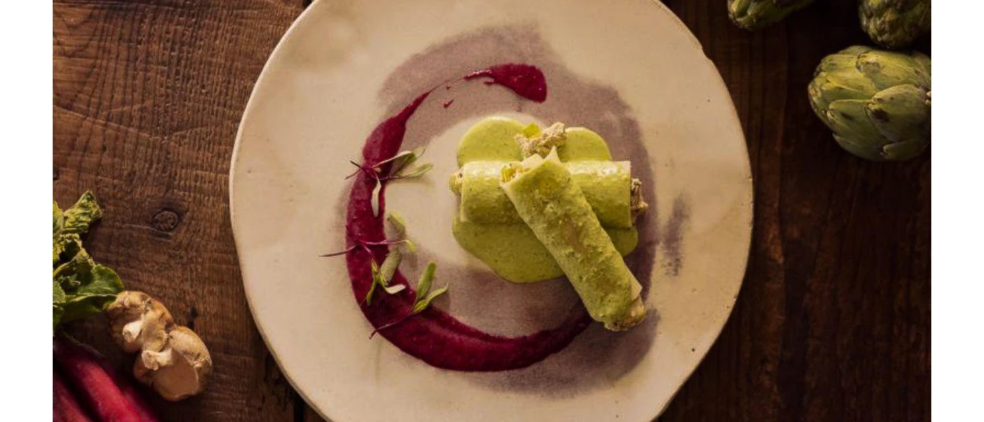 White plate with green roll-like food and a purple sauce garnish