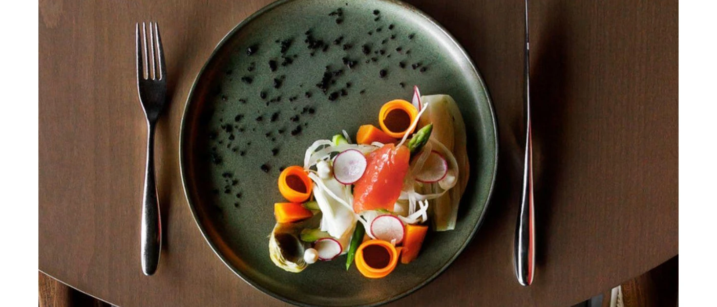 Dark grey plate with smoked salmon, asparagus, carrot coils and onion