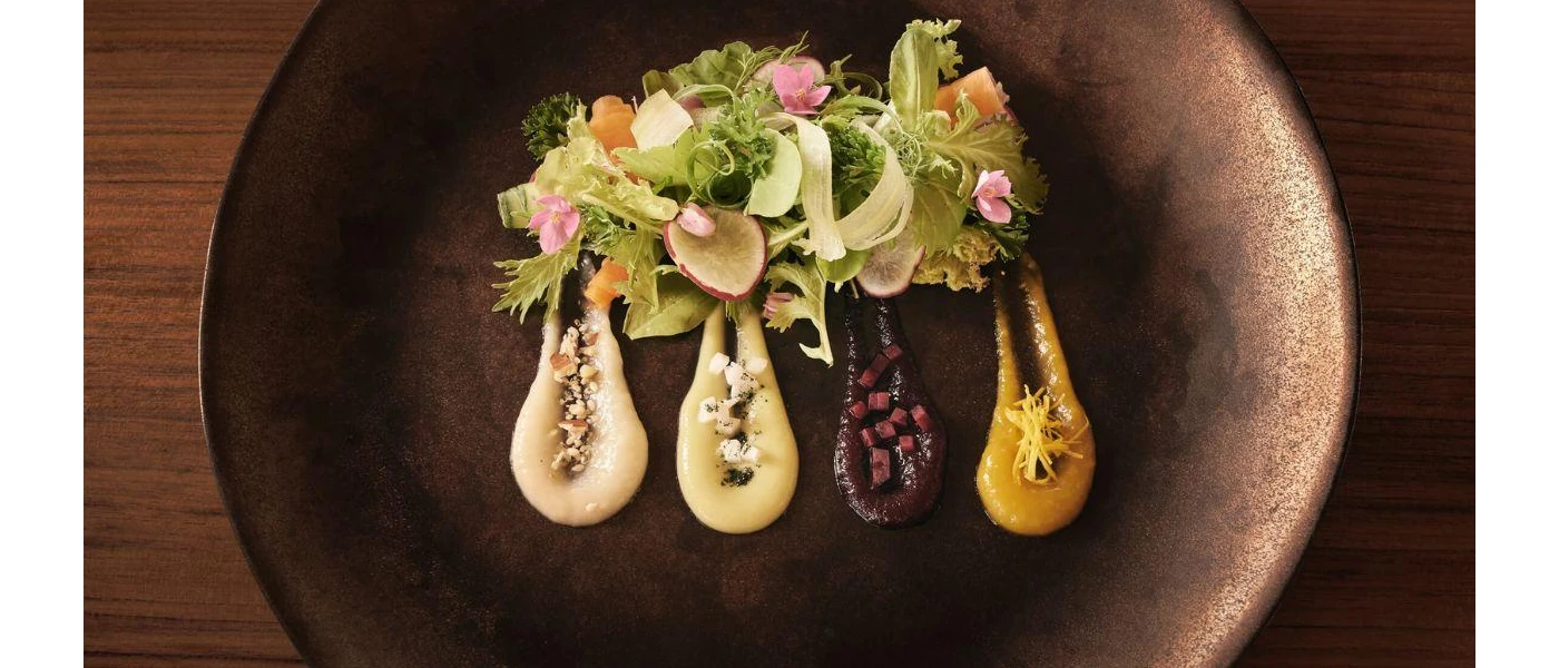 Plate of salad with edible pink flowers and gourmet sauces