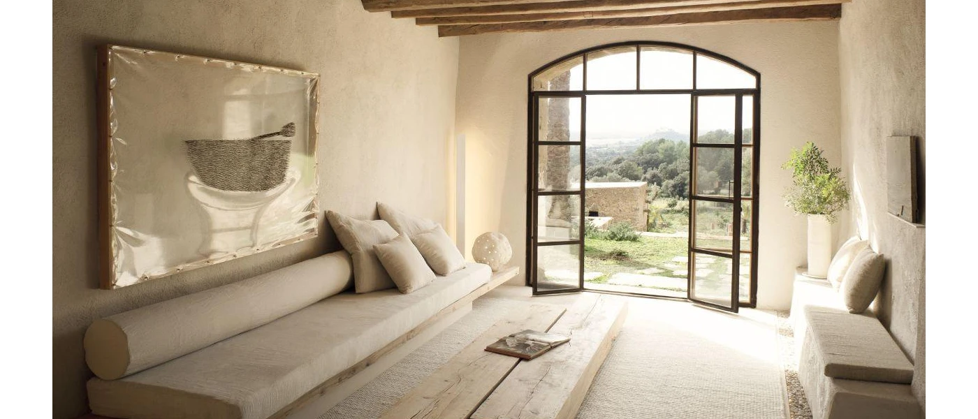 Neutral seating area in a stylish hotel room with black doors opening out to a terrace
