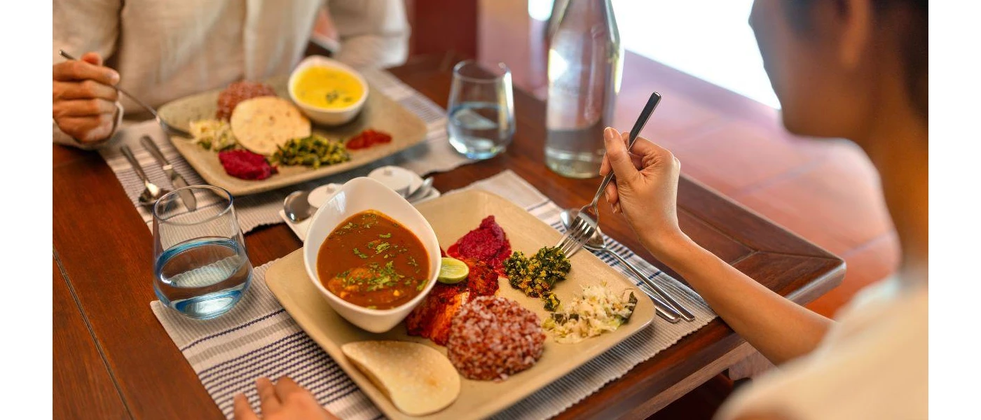 A couple eating together their lunch of different curries in an indoor restaurant
