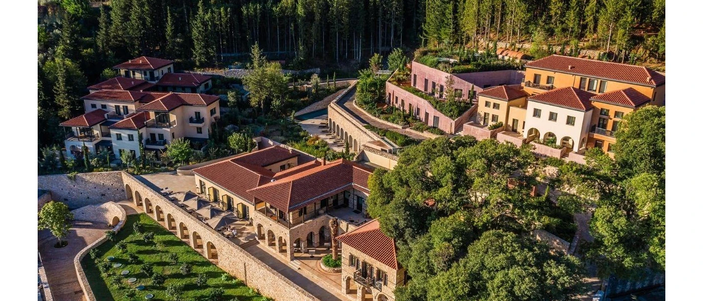 Terracotta-roofed resort on a leafy hillside surrounded by a pine forest