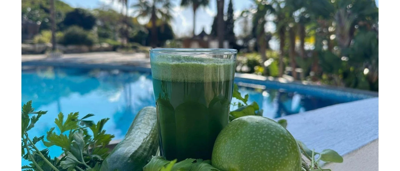 Glass of green juice or smoothie next to a swimming pool