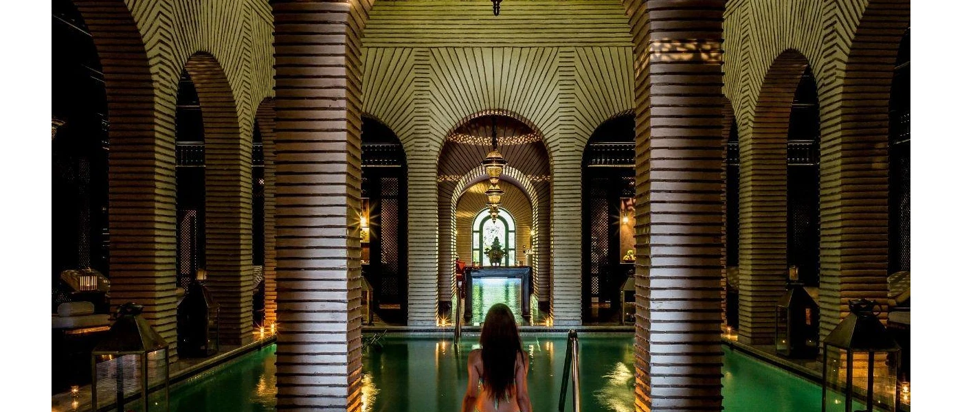Woman standing in front of a pool in a room of pillars and sweeping archways
