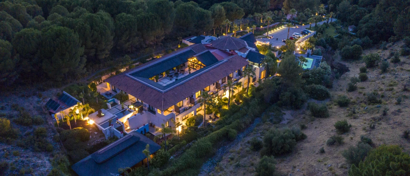 Resort lit up at night surrounded by greenery, as seen from above