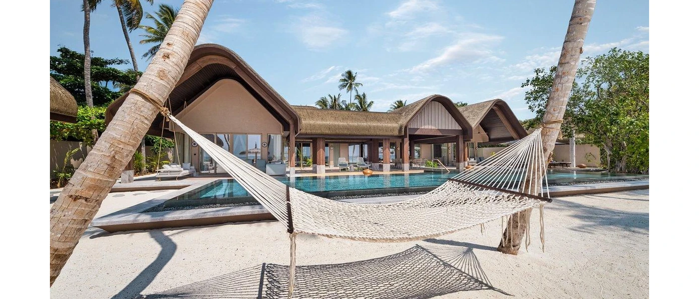 Thatched-roof villas overlooking white sands, and a hammock strung between two palm trees