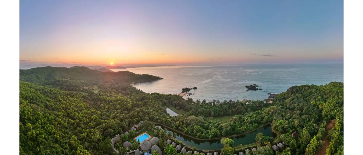 A curvy, golden beach fringed by greenery overlooking the ocean