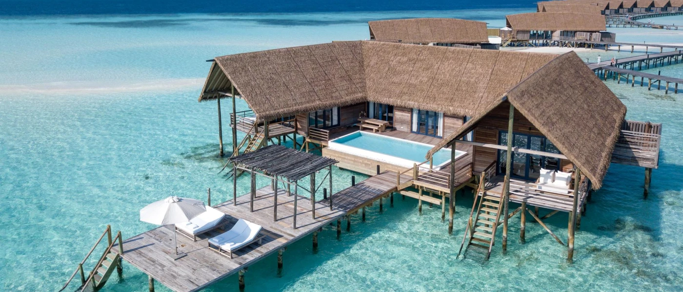 Thatched-roof overwater villas with wooden decks, private pools and steps into a clear blue lagoon