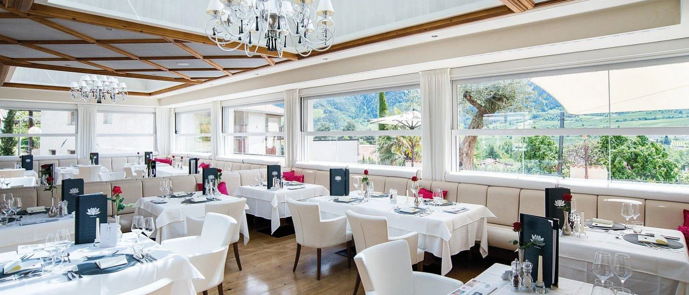 Elegant restaurant with a wood-beamed ceiling, crisp white tablecloths, a chandelier and windows showcasing views of the valley and mountains
