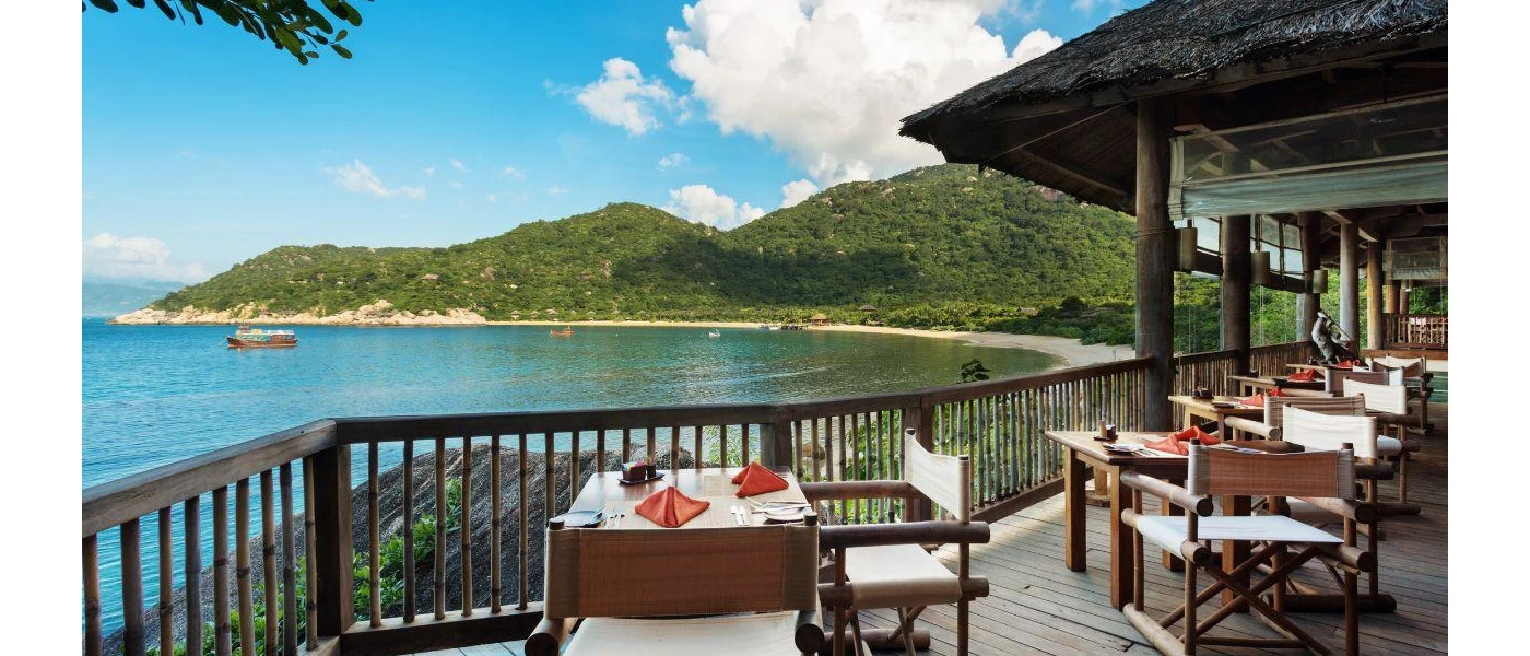 Al fresco wooden restaurant terrace overlooking the sea, with tables laid up with orange napkins