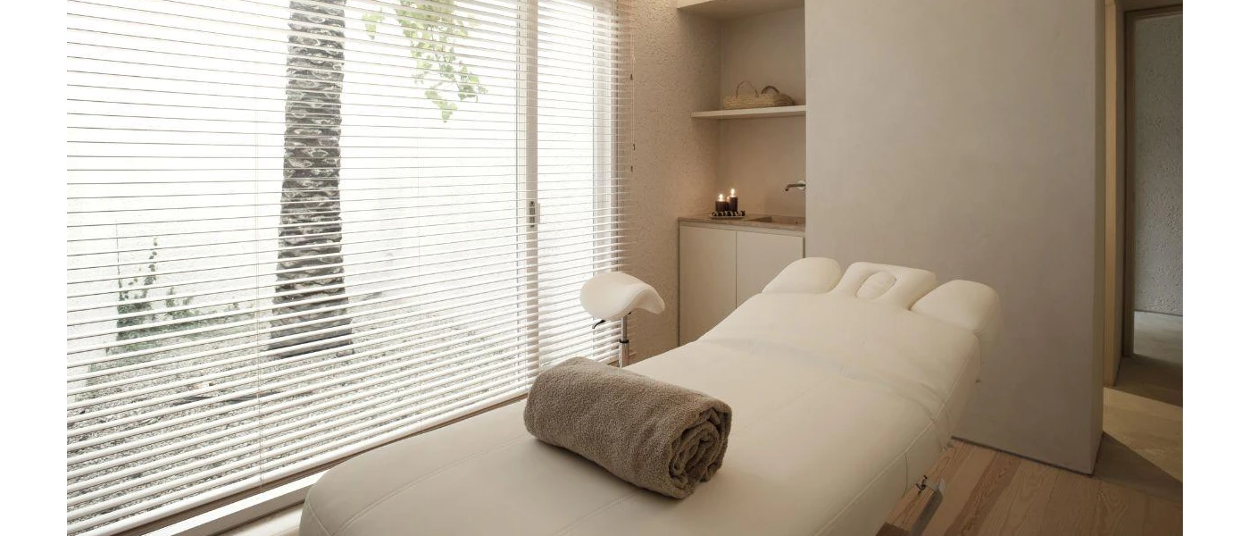Cushioned bed for spa treatments with a brown towel next to a large window