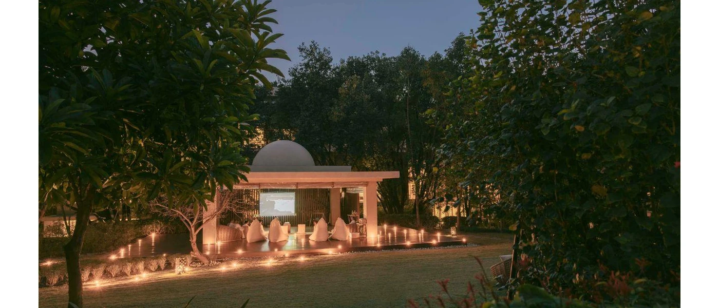 Domed pavilion at twilight, with a cinema screen, white bean bag chairs and candlelight