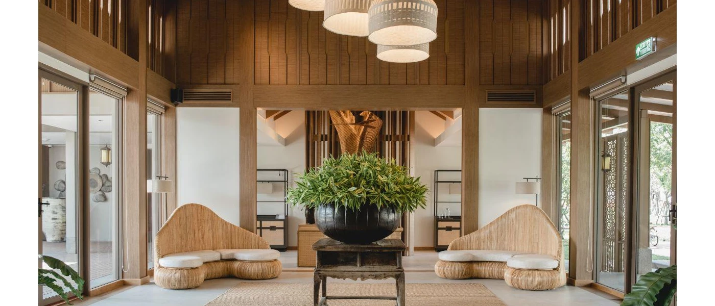 Stylish room with wood-panelled walls and a huge black plant pot with green plants, a jute rug and wooden sofas with white cushions