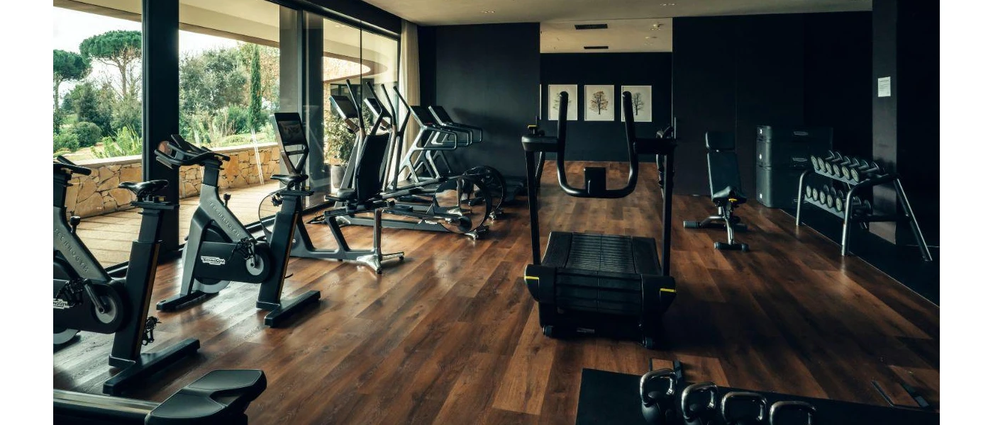 Gym with black walls, wooden floors and black equipment including treadmills, bikes and weights