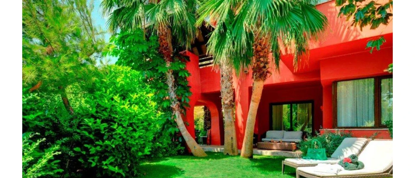 Red-stone accommodation in a tropical garden with white loungers and a sofa