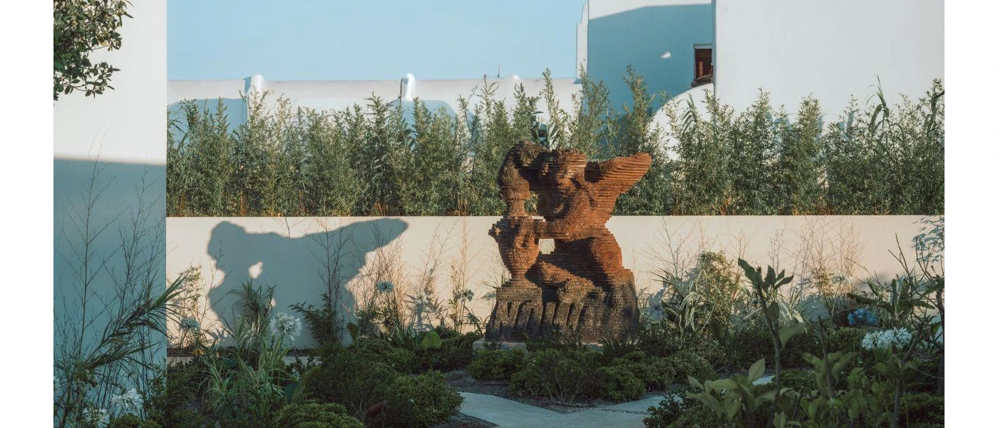 Abstract art sculpture in landscaped grounds under a blue sky