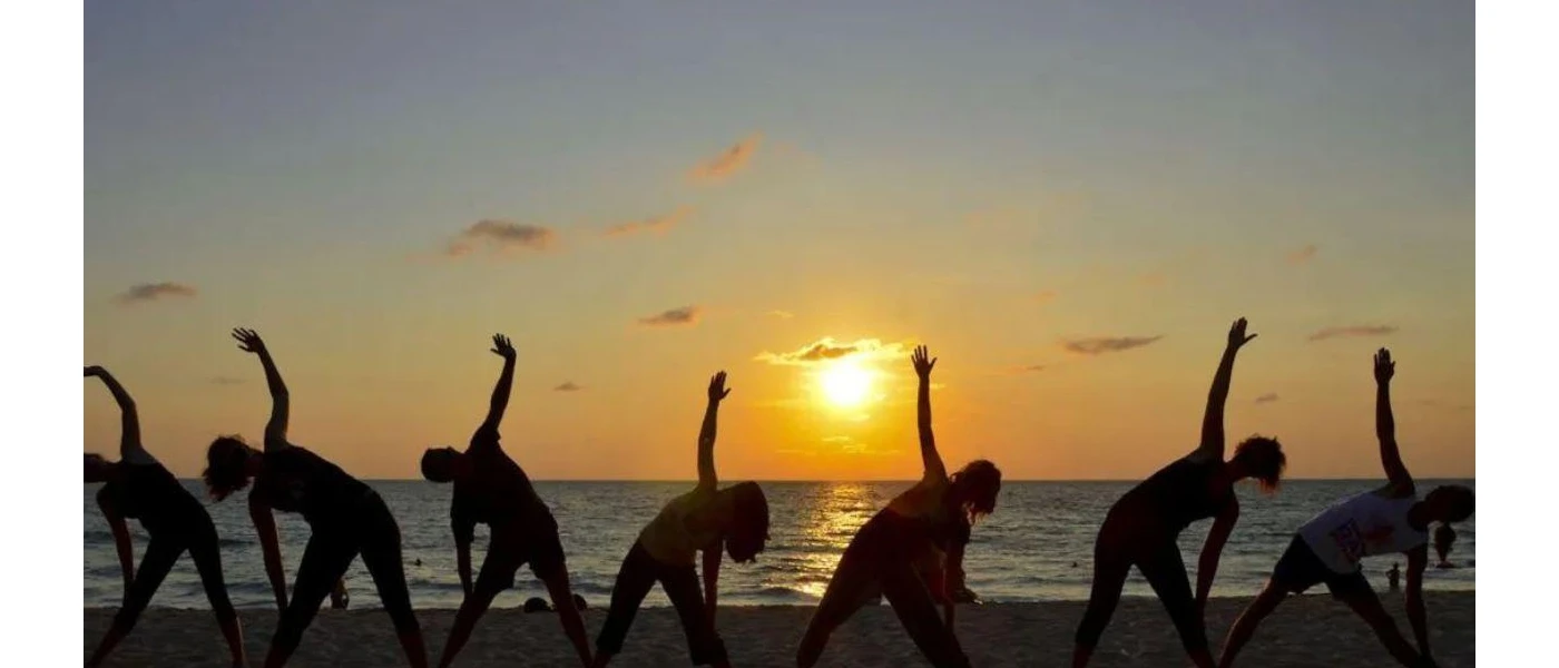 Silhouette of a group enjoying sunset yoga by the water