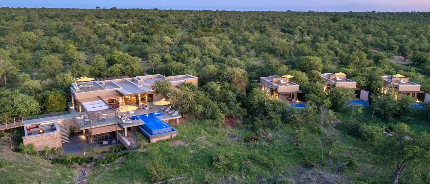 Cube-shaped sand-coloured accommodation units with pools, peeking out from thick greenery