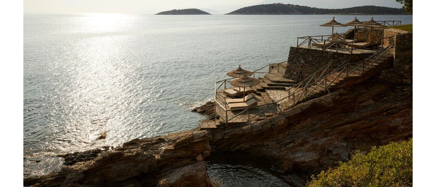 Stone platforms with steps into the sea, lined with thatched parasols and cream loungers
